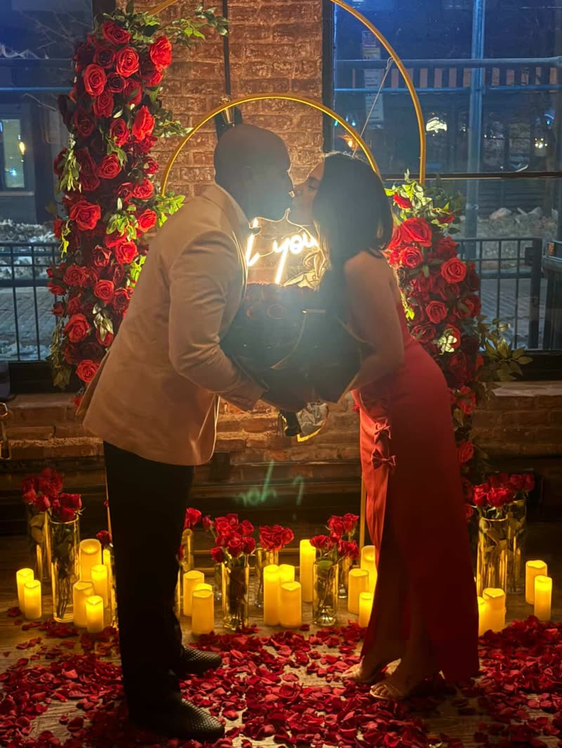 Alexandra and André kissing, surrounded by candles and roses